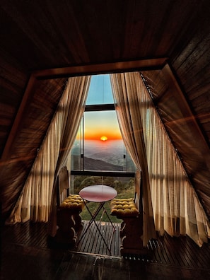 A room with a large window, curtains, a small table, and cushioned seating. - The highest chalet in Brazil and 24 km from Campos do Jordão: Mirante 45 (Santo António do Pinhal)