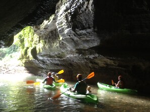 Eine Gruppe Menschen sitzt in Booten und paddelt in einer Höhle.