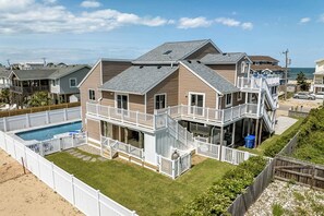 Relax on the spacious balcony or second-level deck, surrounded by a lawn and white picket fence, with access to the ocean.