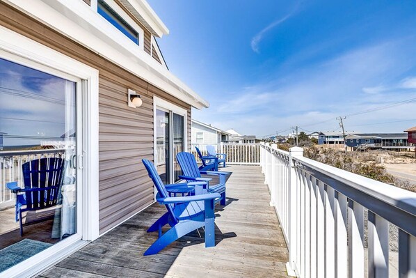 Relax in style on this spacious deck with comfortable Adirondack chairs and a sliding glass door leading to the interior.