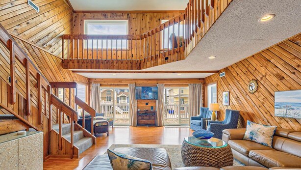 Un vaste espace de vie agrémenté d’un escalier en bois, d’un canapé confortable et d’une grande fenêtre donnant sur l’extérieur.