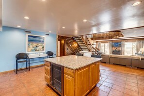 Spacious living area with a large island counter, oven, and wooden staircase.