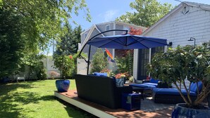 A patio area with outdoor furniture, a large umbrella, and potted plants. - Beautiful Free-Standing Cottage, In The Heart of Provincetown.  (Provincetown)