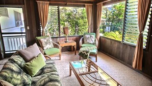 A cozy room with a sofa, two chairs, a small table, and large windows with curtains.