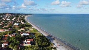 Una vista aerea di una cittadina costiera con una spiaggia lunga, case e un faro.