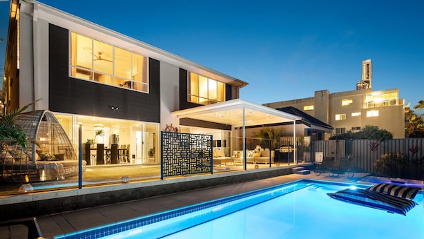 Une maison moderne dotée d’une piscine, d’un espace salon extérieur et d’un patio couvert.