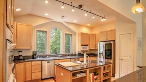 Una cocina moderna con armarios de madera, un refrigerador de acero inoxidable y una isla grande con un lavamanos.