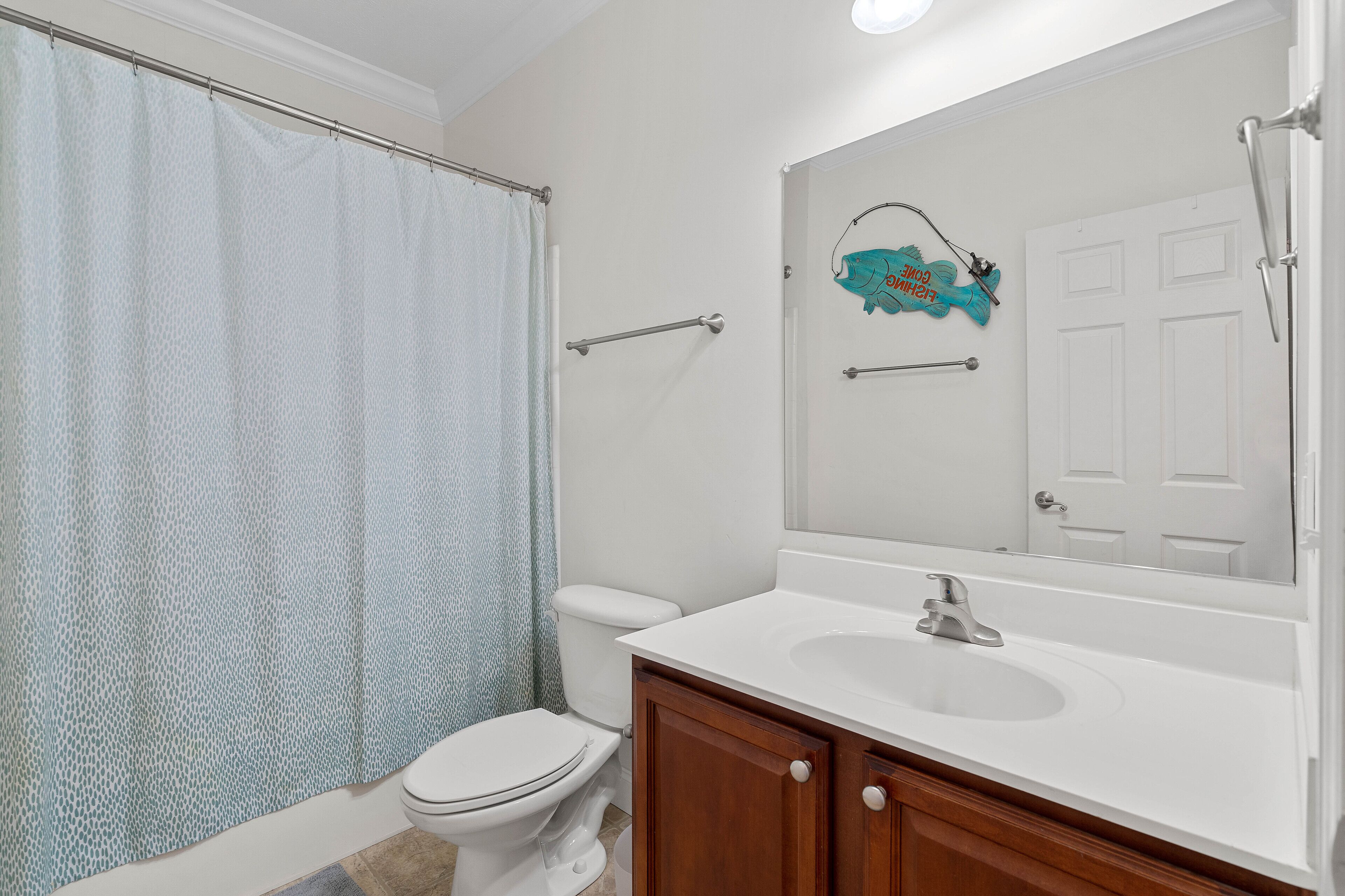 Une salle de bain équipée d’une douche avec rideau, de toilettes, d’un lavabo et d’un miroir avec un porte-serviettes.