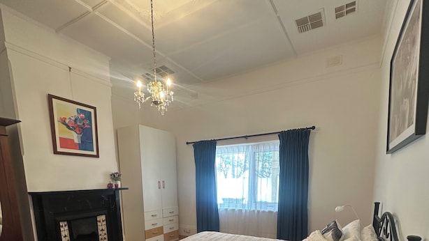Una camera da letto con un letto grande, un camino, un lampadario e una finestra con tende.