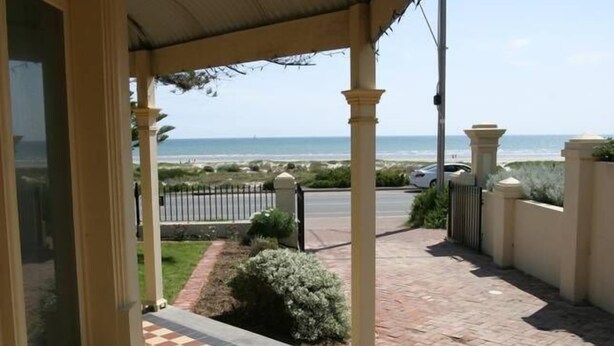 A covered outdoor area with a view of the beach, a paved walkway, and a fence. - Esplanade Beach House with beautiful sea views (Semaphore)