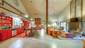 A spacious living room with a fireplace, a dining area with red cabinets, and a kitchen with red appliances.