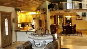 A cozy interior with a wooden ceiling, a dining area with a table and chairs, and a kitchen with wooden cabinets and a countertop.