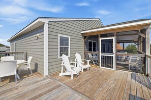 A deck with outdoor furniture, a covered area, and a building with windows.
