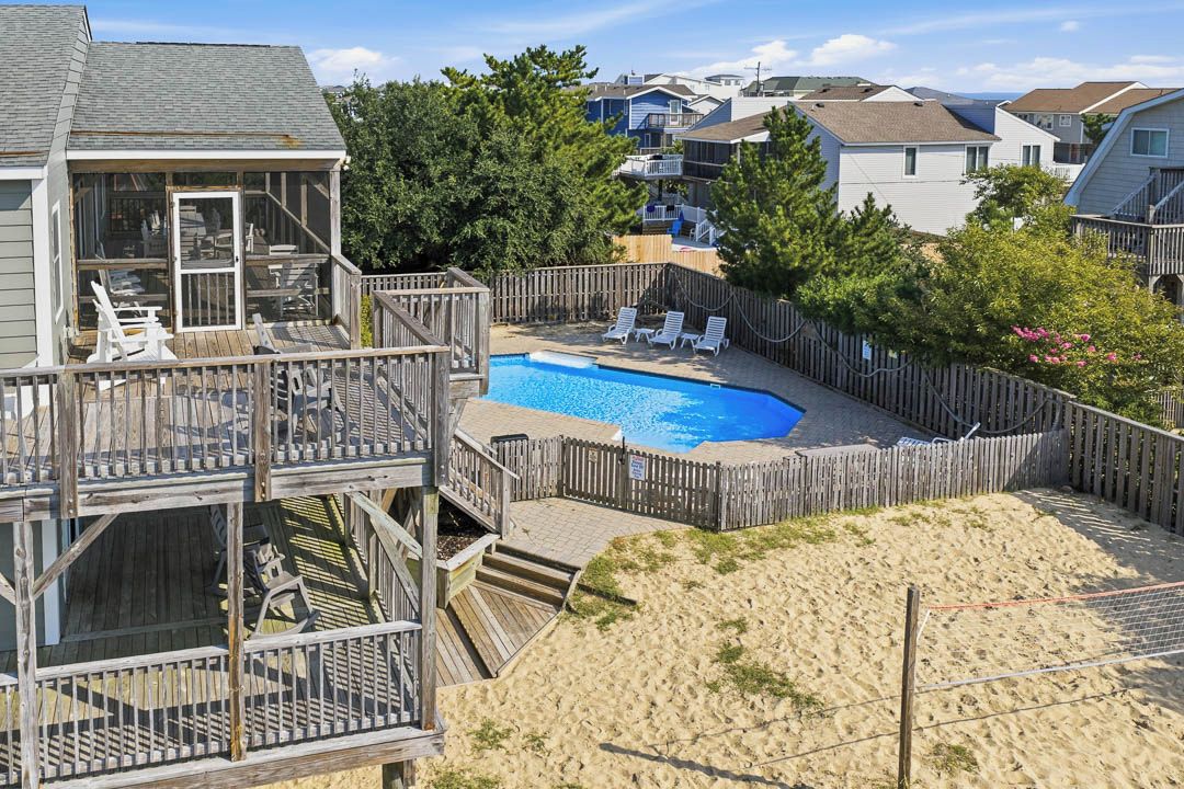 A residential area with a swimming pool, wooden deck, and a view of neighboring houses.