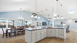 A spacious kitchen with a large island, white cabinetry, and pendant lighting.