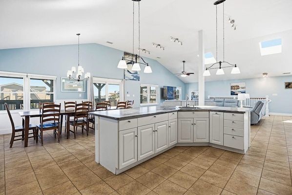 A spacious kitchen with a large island, white cabinetry, and pendant lighting. - Cabana Royale | 520 ft from the beach | Private Pool (Virginia Beach)