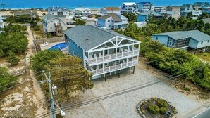 A coastal residential area with a prominent two-story house featuring a balcony with outdoor seating.
