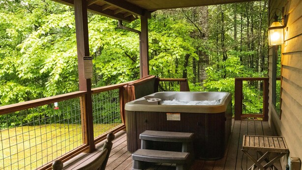 A hot tub on a wooden deck with a view of a forest.