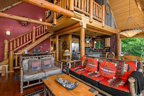 Ein rustikales Cabin-Interieur mit einer Holztreppe, einer Couch mit gemusterten Kissen und einem Essbereich.