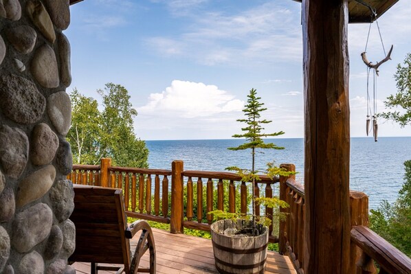 A wooden deck with a stone wall, a wooden chair, and a potted plant.