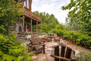 Eine Holzterrasse mit Sitzgelegenheiten im Freien, umgeben von üppiger Vegetation und einer Steinmauer.