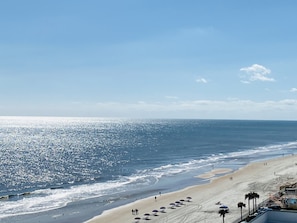 A beach with a clear sky, sandy shore, and umbrellas.