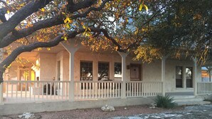 A white building with a porch, stone pathway, and a large rock in the foreground.