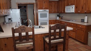 A kitchen with wooden cabinets, a white countertop, a sink, a microwave, and a stove.
