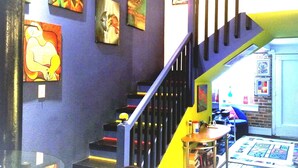 A staircase with a black railing, surrounded by various artworks on the walls. - The Gallery Getaway in the Heart of Historic, Riverfront Wilmington!  (Wilmington)