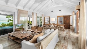 A spacious living area with a large sofa, wooden coffee table, and dining set. - Sueno De Mar: Beachfront Villa for 10 (Hartswell)