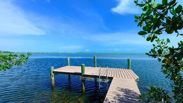 A wooden dock extending into calm waters with clear skies. - Private Oceanfront Cottage with dockage, pool just minutes to Key West! (Cudjoe Key)