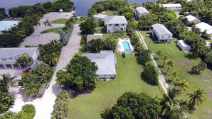 An aerial view of a residential area with houses, a swimming pool, and a beach. - Private Oceanfront Cottage with dockage, pool just minutes to Key West! (Cudjoe Key)