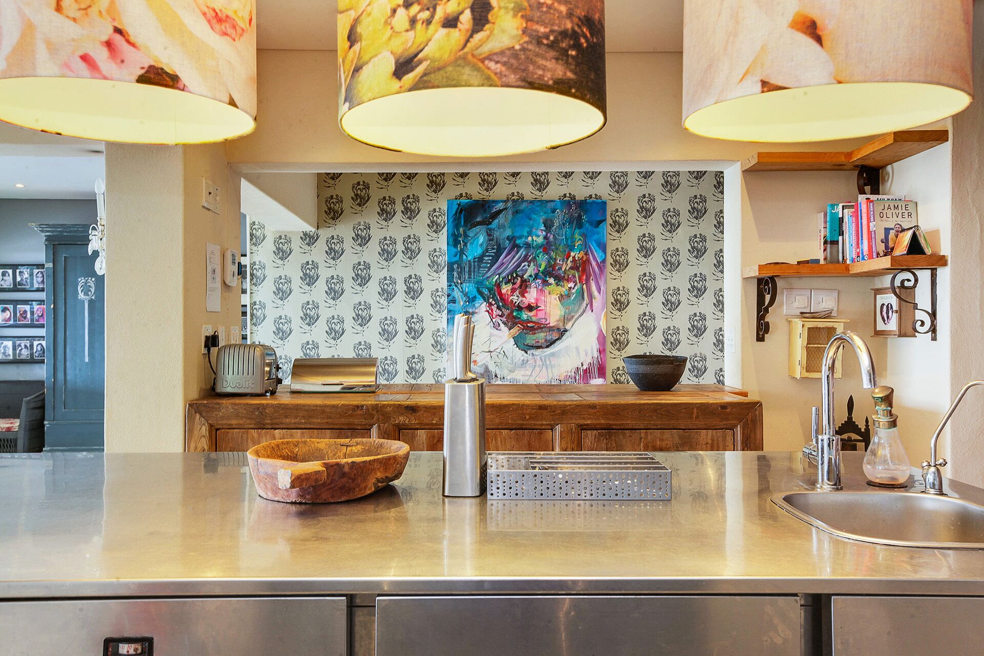 A kitchen with a central island, a sink, and a backsplash with a floral pattern.