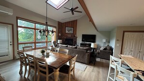A spacious living area with a dining table, chairs, a fireplace, a television, and a ceiling fan. - A Breath of Fresh Air—Weekend Plans at the Timberview (Carroll)