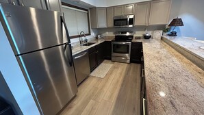 A modern kitchen with stainless steel appliances, wooden flooring, and light-colored cabinetry. - A Breath of Fresh Air—Weekend Plans at the Timberview (Carroll)