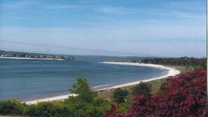A coastal landscape with a beach, a clear sky, and distant houses. - The Waterfront Deckhouse-Pine Point Beach Waterfront Property (Scarborough)
