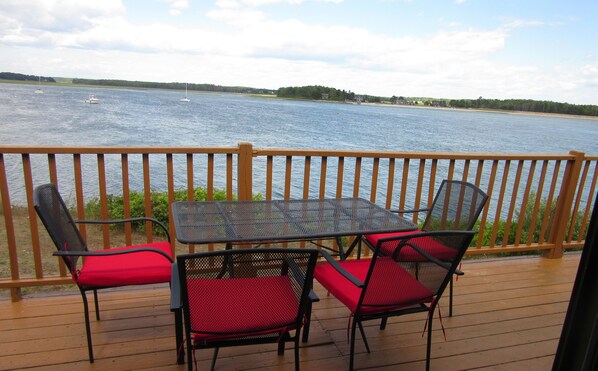 Enjoy a waterfront view from this deck with a table and chairs, surrounded by a railing for safety.