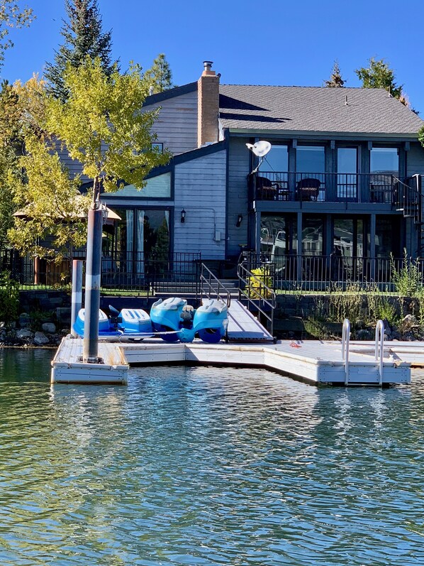 A dock with kayaks, a building with large windows, and a clear blue sky.