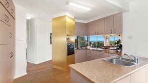 A modern kitchen with granite countertops, stainless steel appliances, and a view of the outdoors. - MYSTIC WAVES | WIFI , Pet Friendly | Accom Holidays (WAMBERAL)