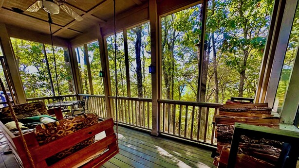 A wooden deck with a sofa and a table, overlooking a forested area. - WNC’s Breathtaking Blue Ridge & Great Smokies meet the SC Jocassee Gorges (Rosman)