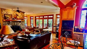 A spacious living room with a fireplace, a dining area, and a kitchen with wooden cabinets. - WNC’s Breathtaking Blue Ridge & Great Smokies meet the SC Jocassee Gorges (Rosman)