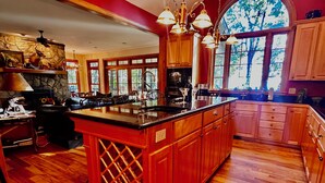 A spacious kitchen with a large island, wooden cabinets, and a stone accent wall. - WNC’s Breathtaking Blue Ridge & Great Smokies meet the SC Jocassee Gorges (Rosman)