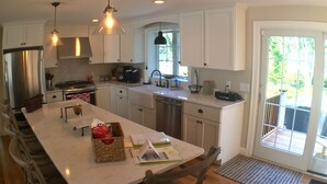 Een moderne keuken met witte kasten, roestvrijstalen apparatuur en een groot keukenblok met zitplaatsen.