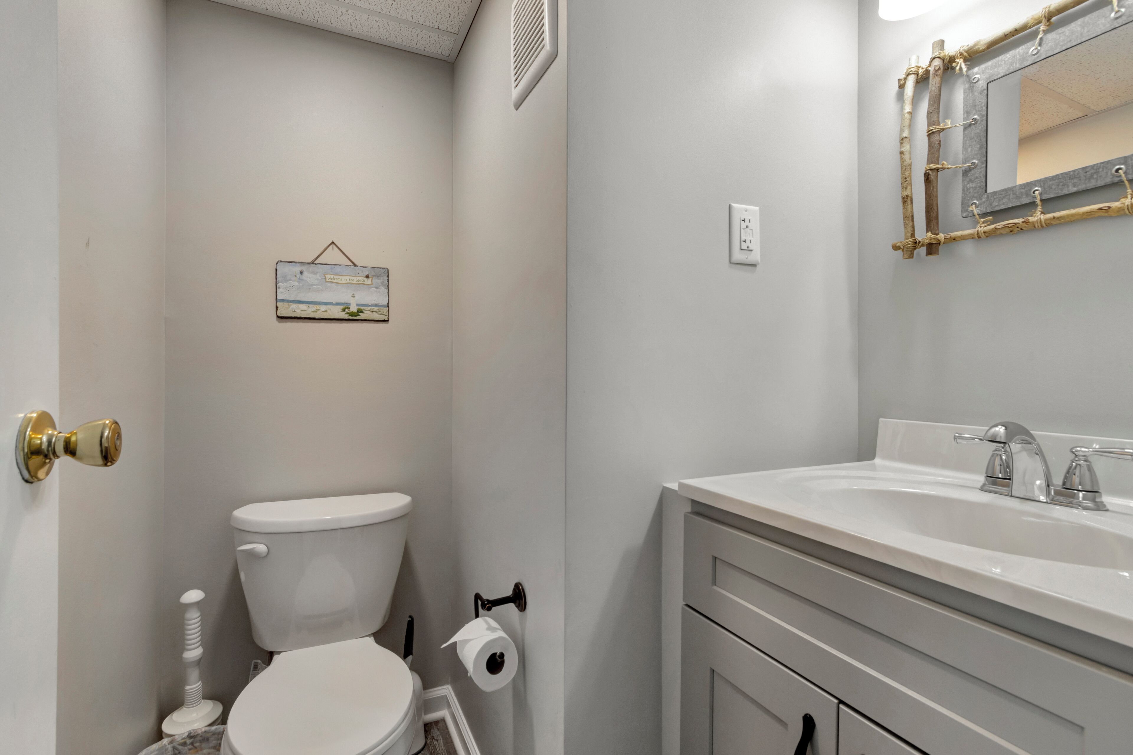 A bathroom with a toilet, sink, and mirror.