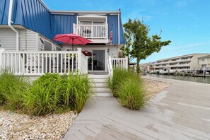 A waterfront building with a balcony, a red umbrella, and a dock with boats. - Bayside Retreat w/ Dock, Pool Access & 10 Min Walk to Beach! (Ocean City)