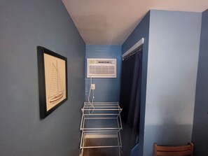 Cozy retreat with a sailboat print, air conditioning unit, and drying rack.