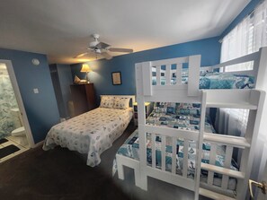 Cozy room with a bunk bed and single bed, featuring a ceiling fan, nightstand, and framed picture.