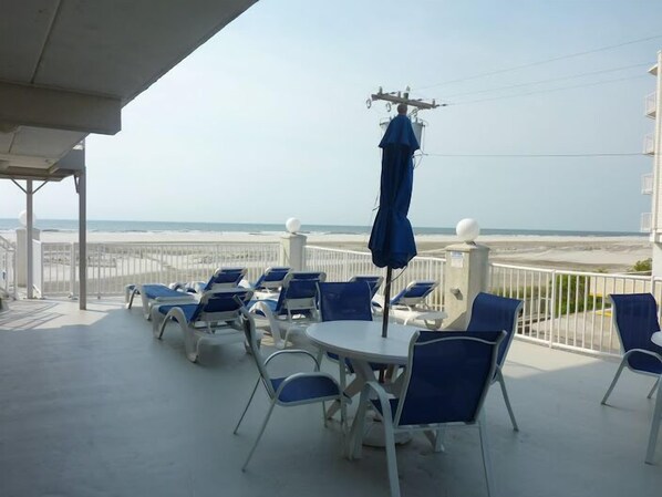 Enjoy the serene beach views from this seaside terrace, featuring comfortable seating and umbrellas.