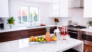 Une cuisine moderne dotée d’un plan de travail en marbre, d’un panier de fruits, d’une cave à vin et d’une cuisinière.