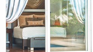 Une chambre avec un lit, une table de chevet et une vue sur une piscine, visible à travers une porte vitrée.